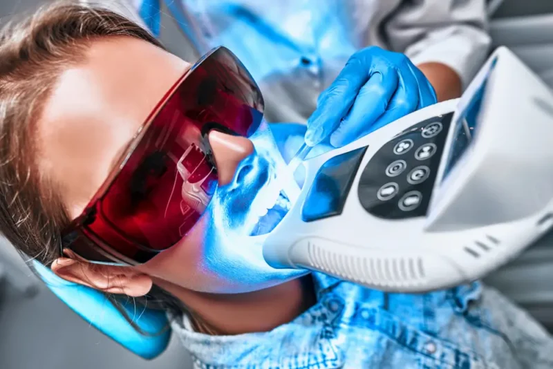 Close-up of a patient receiving UV-lighting on her teeth bonding during a dental procedure